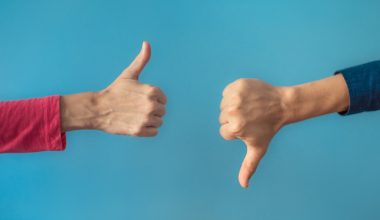 Two hands in front of a blue wall. One is giving a thumbs up and the other is giving a thumbs down.